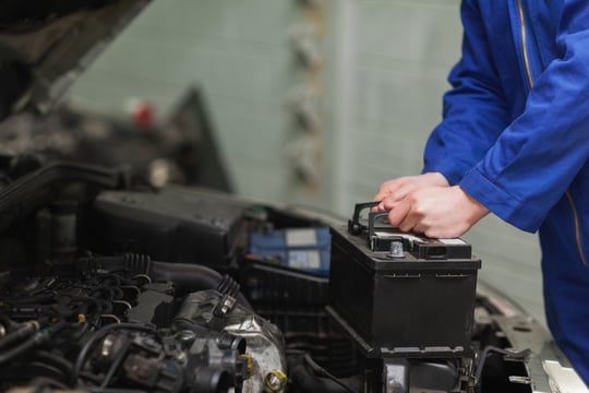 Male mechanic changing car battery